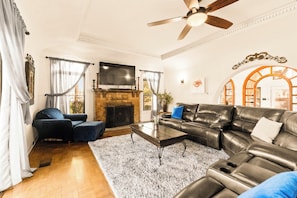 A living room with a fireplace, leather sofa, and a flat-screen TV. - Casa Canasa in charming San Antonio!!!! Must see!!! (San Antonio)
