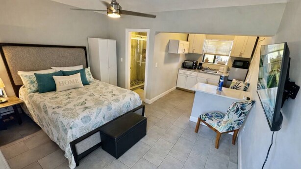 Une chambre comprenant un lit, un bureau, une chaise, une télévision et un coin cuisine.
