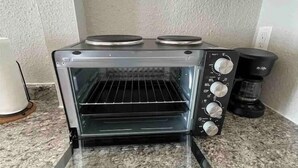 Une cuisine équipée d’un four électrique encastré, d’une machine à café et d’un meuble blanc placé au-dessus du four.