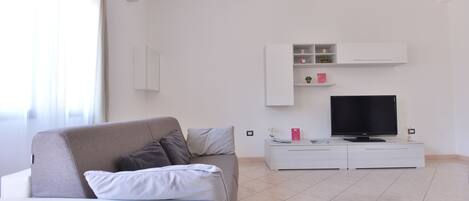 Una sala de estar moderna con sofá, televisor y mueble de almacenamiento.