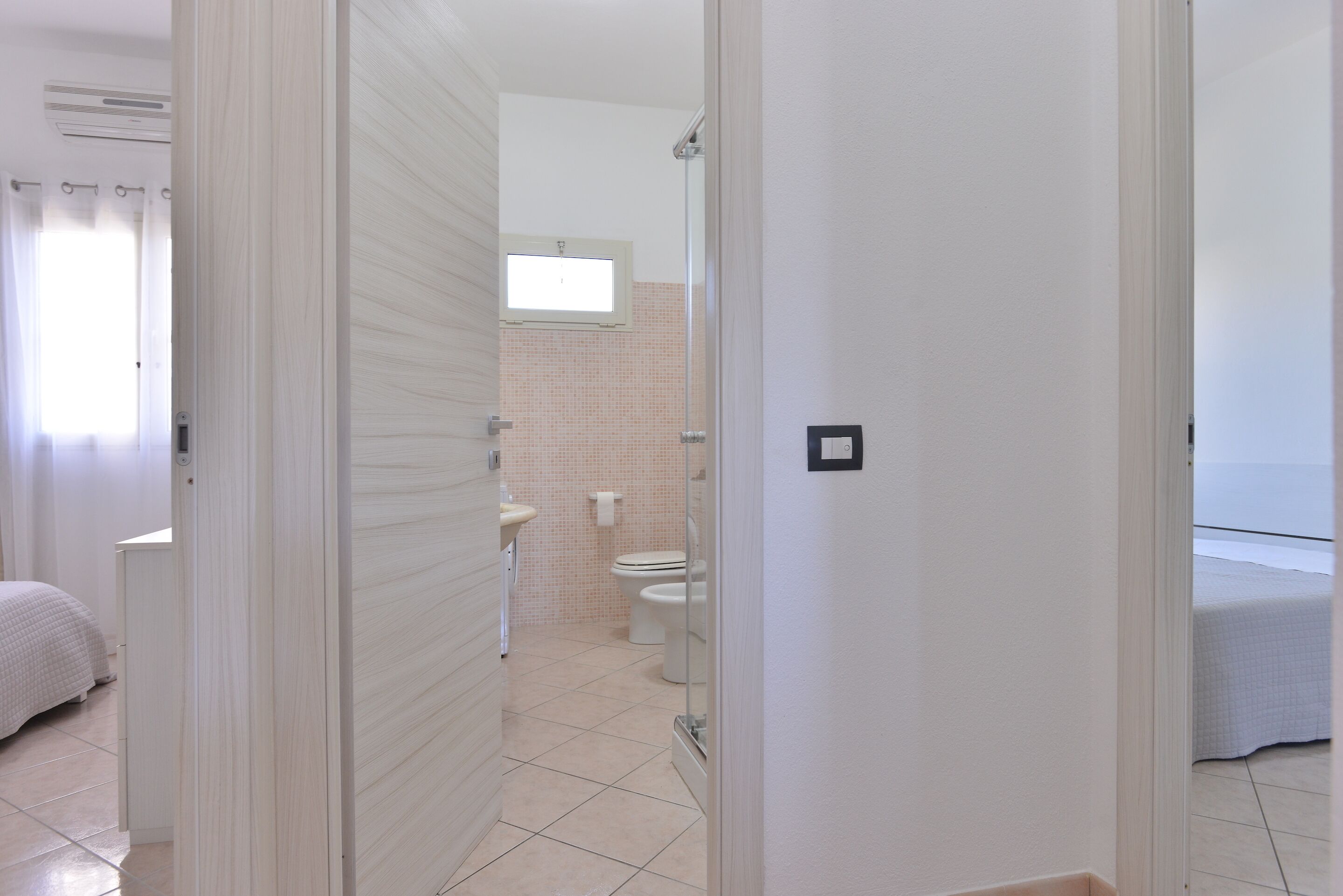 A hotel room with a bed, a bathroom with a toilet and sink, and a window.