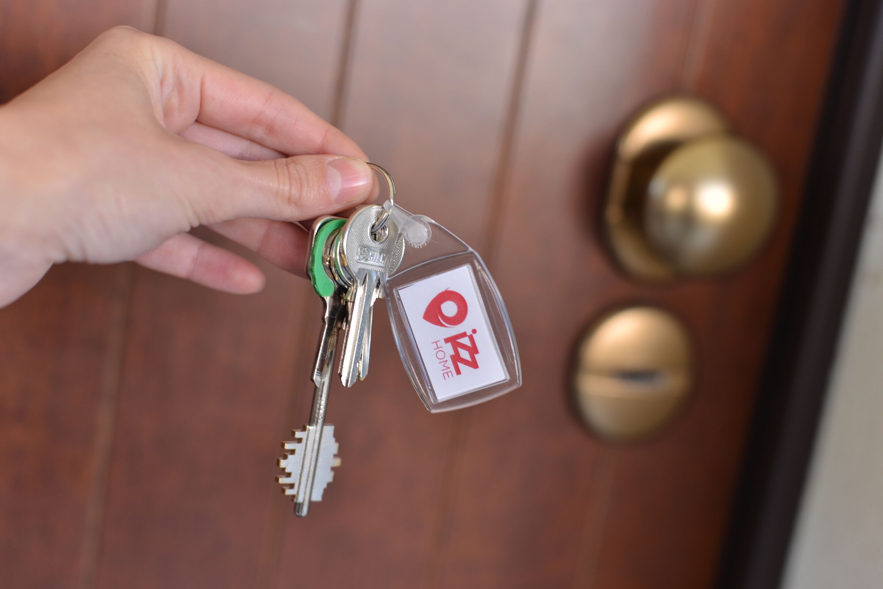 A hand holding a set of keys with a keychain that has a red and white logo.