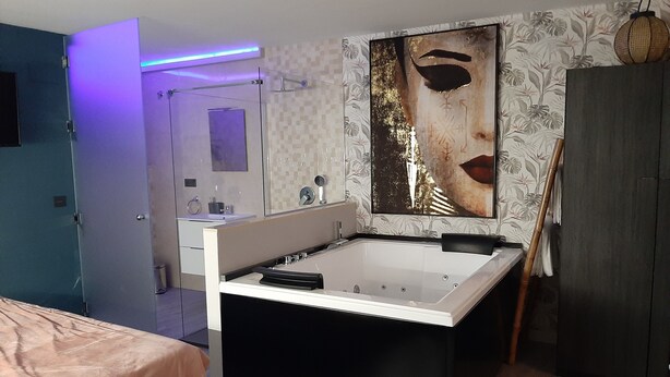 A modern bathroom with a freestanding bathtub, a large mirror, and a decorative wall piece. - Sierra Lof Paradise Apartment (Ubrique)