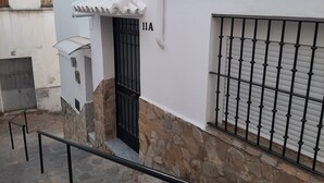 A narrow alleyway with a stone wall, a black gate, and a metal railing. - Sierra Lof Paradise Apartment (Ubrique)