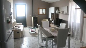 A modern living room with a dining area, a sofa, a TV, and a kitchen area with a fridge. - House Mary, 15 minutes from the splendid beaches of Sinis - IUN Q1172 (Nurachi)