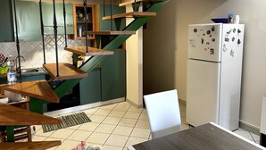 A kitchen with a wooden staircase, a white refrigerator, and a dining area with a table and chairs. - House Mary, 15 minutes from the splendid beaches of Sinis - IUN Q1172 (Nurachi)