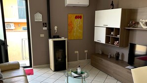 A living room with a sofa, a glass coffee table, a fireplace, a TV, and a wall-mounted shelf. - House Mary, 15 minutes from the splendid beaches of Sinis - IUN Q1172 (Nurachi)