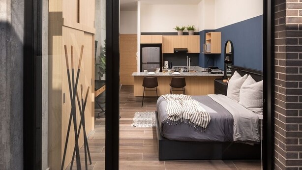 Un apartamento moderno con puerta de vidrio que da a un dormitorio y una kitchenette.