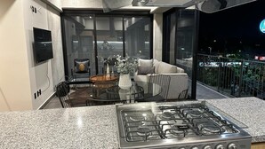 Una cocina moderna con estufa a gas, horno empotrado y zona de comedor de vidrio.