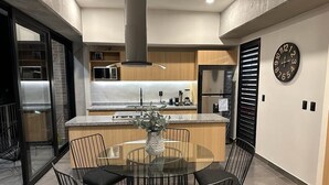 Una cocina moderna con una mesa redonda, sillas negras y un reloj en la pared.