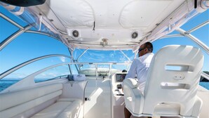 A boat's interior with a steering wheel, control panel, and seating.