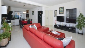 A modern living room with a red sofa, a dining area, a kitchen, and a TV. - Villa Blanka - Six Bedroom Villa with Swimming Pool and Sea View (Podgora)