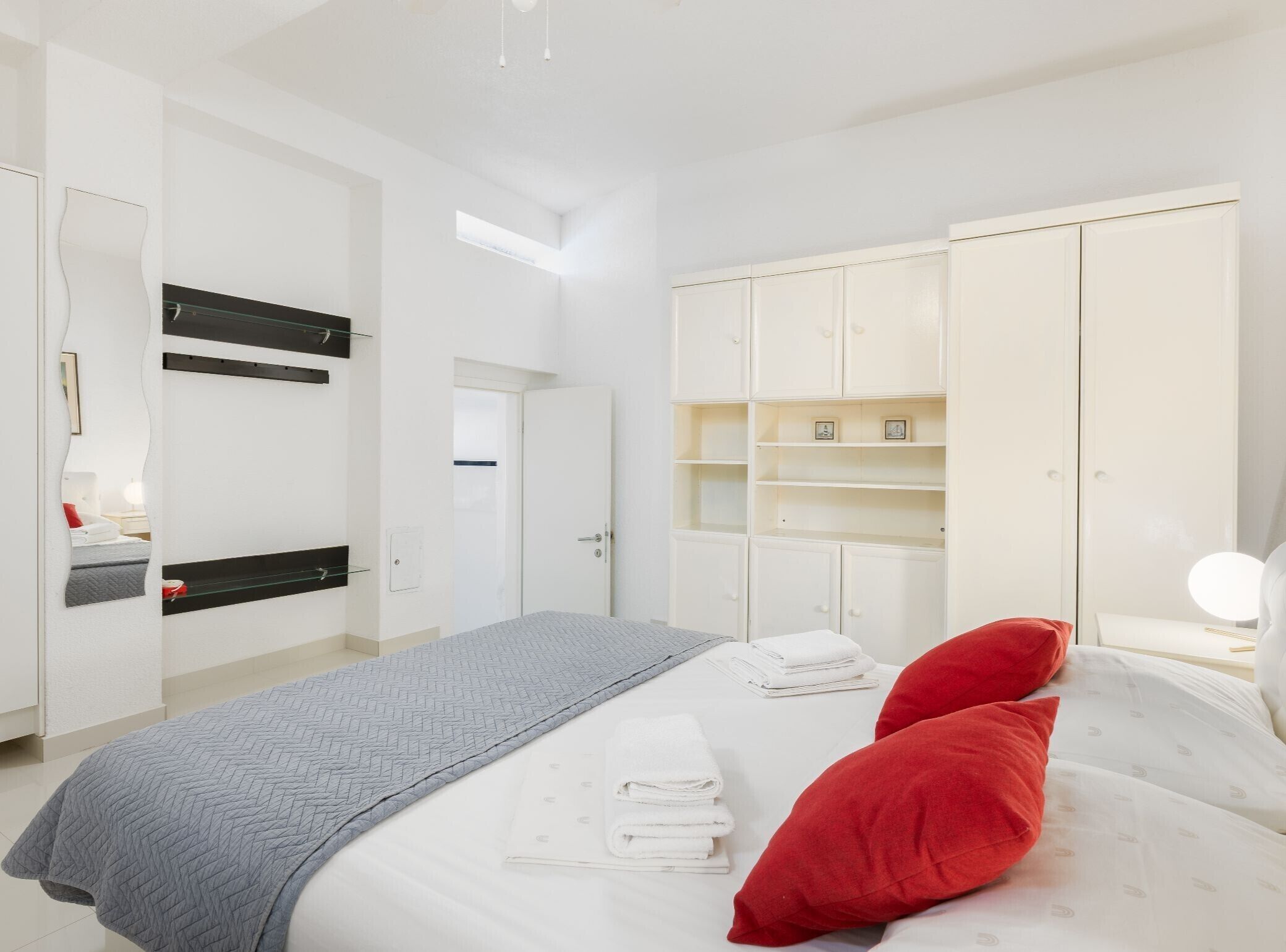 Un dormitorio moderno con cama, armario y espejo.