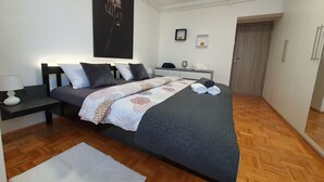Un dormitorio moderno con una cama grande, una mesita de noche, un armario y una puerta.