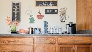 Eine Küchenzeile mit Kaffeemaschine, einem Schild mit Kaffeemotiv und einem Topfpflanzen.
