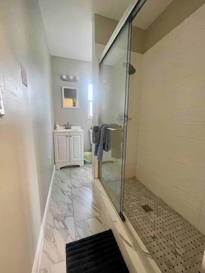 Une salle de bain avec une porte de douche en verre, un lavabo et un miroir.