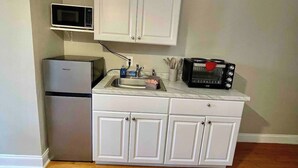 Cocina compacta equipada con refrigerador, microondas y horno tostador.