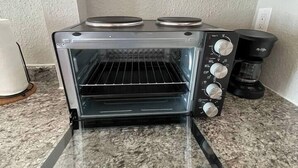 Une cuisine équipée d’un four à grille-pain encastré, d’une machine à café et d’un meuble blanc.