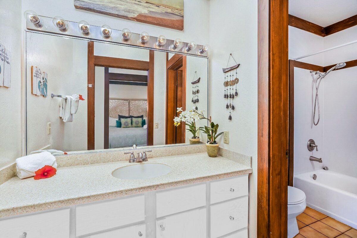Un baño con un espejo grande, tocador y bañera.