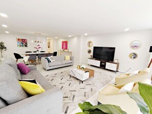 A modern living room with a grey sofa, a coffee table, and a flat-screen TV.