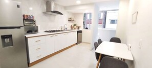 A modern kitchen with a built-in oven, microwave, and gas stove. There is a dining area with a table and chairs.