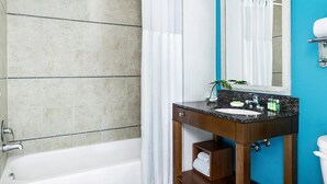 A bathroom with a bathtub, a sink with a mirror, and a toilet.