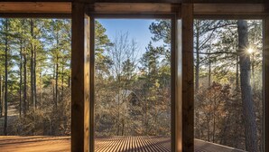 Eine Hütte mit großen Fenstern, die Blick auf ein bewaldetes Gebiet bieten.