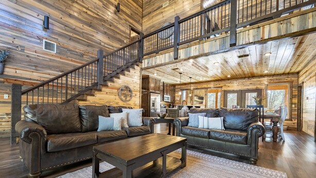 Ein geräumiges Wohnzimmer mit zwei Ledersofas, einem Holztisch und einer Treppe, die in ein Obergeschoss führt.