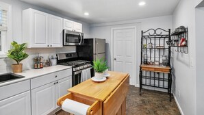 A compact kitchen with white cabinets, a stainless steel stove, and a wooden island. - Walk to Bridge Street from the Westside Charmer! (Grand Rapids)