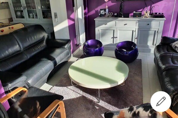 A living room with a black leather sofa, a green coffee table, and purple exercise balls.