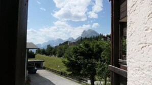 A view from a window overlooking a mountain landscape with a building in the foreground. - Newly renovated, cozy apartment with a beautiful balcony - NEST'L Appartements (Mösern)