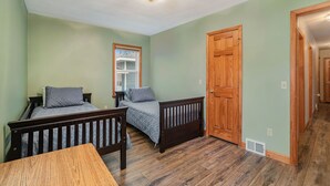 Un dormitorio con dos camas, una mesa de madera y una puerta que da a otra habitación.