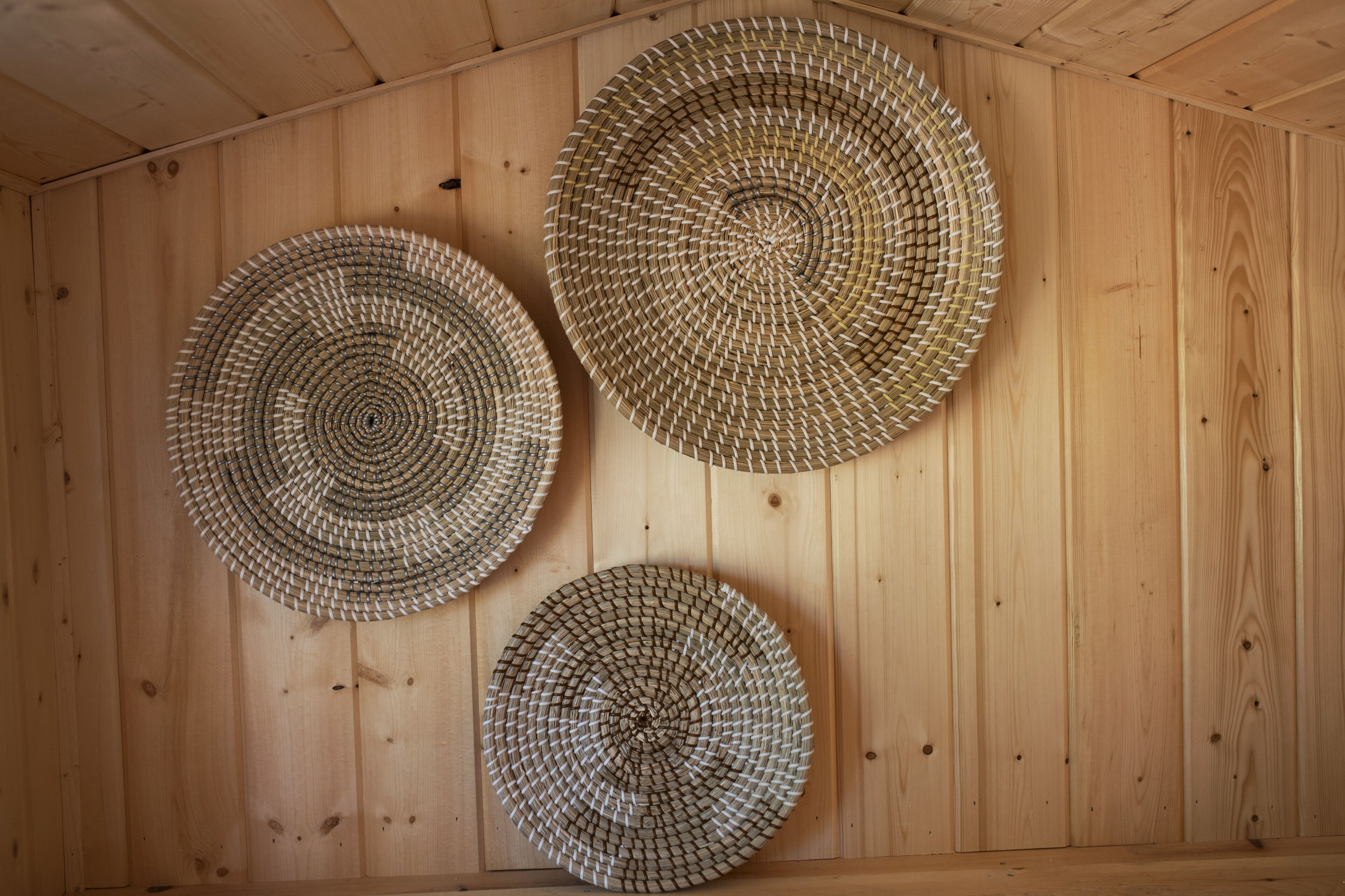 Three circular woven mats on a wooden wall.