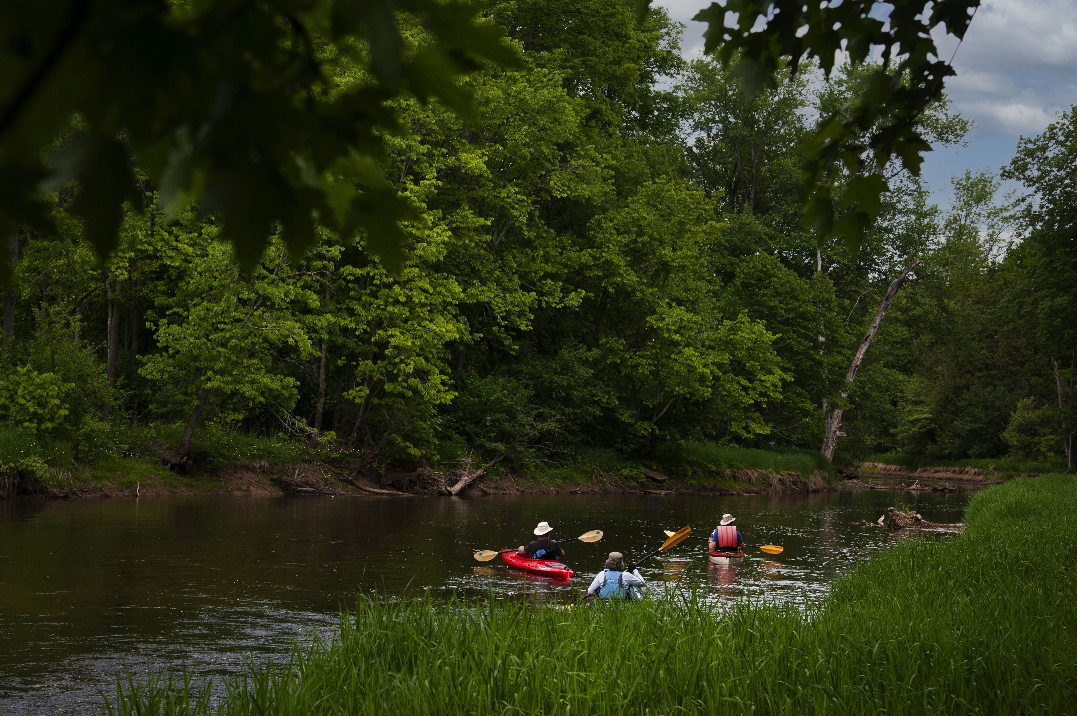 A calm river with kayaks and a person paddling.