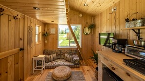 A cozy cabin interior with a wooden interior, a sofa with patterned cushions, a small table, and a television. - Boho Beaver (Grey Highlands)