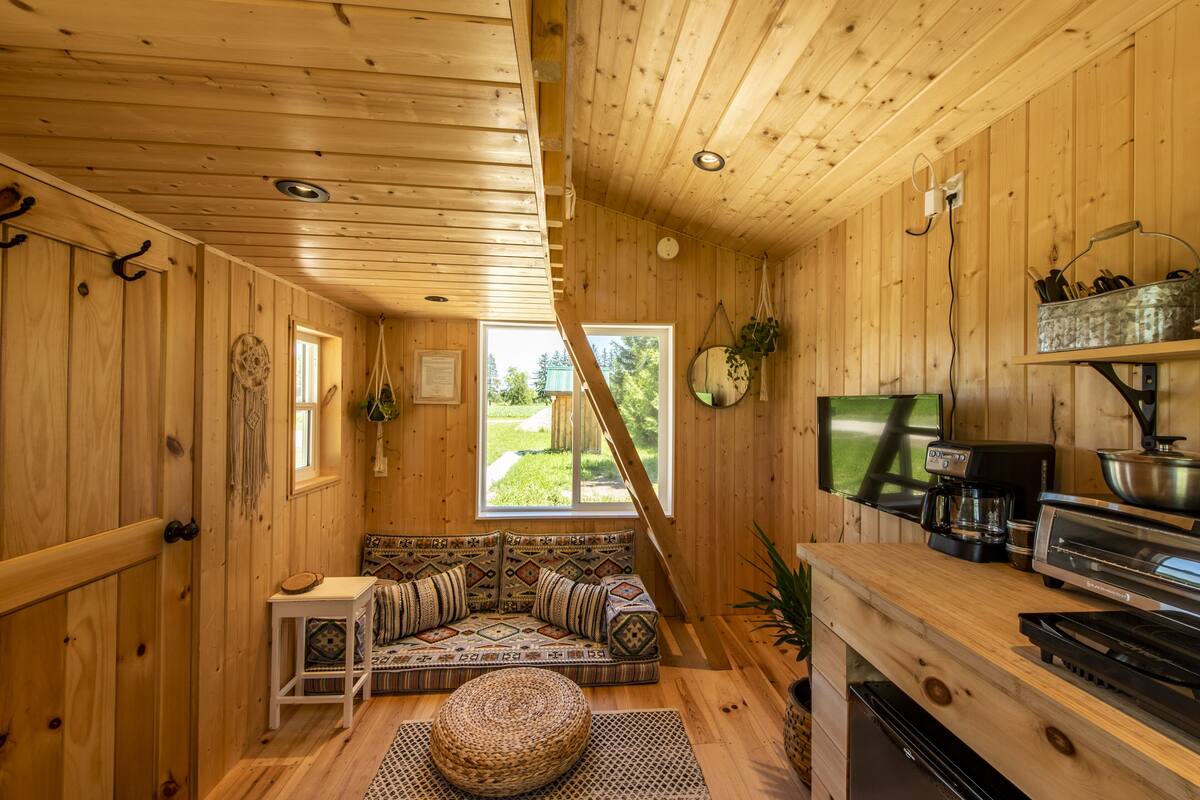 A cozy cabin interior with a wooden interior, a sofa with patterned cushions, a small table, and a television.