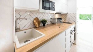 A modern kitchen with a herringbone tile backsplash, a stainless steel sink, a microwave, and a small potted plant. - Nice: Superb apartment in the Carré d'Or. (Nice)