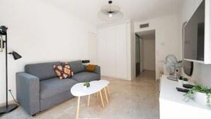 A modern living room with a grey sofa, a small white table, and a ceiling light fixture. - Nice: Superb apartment in the Carré d'Or. (Nice)