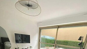 A modern bedroom with a bed, a TV, a desk, and a large window. - Nice: Superb apartment in the Carré d'Or. (Nice)