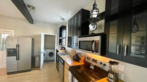 A modern kitchen with stainless steel appliances, wooden countertops, and black cabinets.