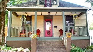 A two-story house with a front porch, a red door, and a small balcony.