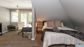 A bedroom with a bed, a desk, a chair, and a window.
