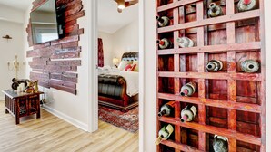 A room with a wooden wall, a bed, a TV mounted on the wall, and a wine rack. - Family Beach Home ~Steps to Beach~Hot Tub~Game Room~Sleeps 13! (Surf City)