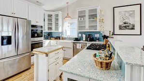A modern kitchen with white cabinetry, stainless steel appliances, and a blue speckled countertop. - Family Beach Home ~Steps to Beach~Hot Tub~Game Room~Sleeps 13! (Surf City)