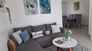 Un soggiorno moderno con un divano ad angolo grigio, un tavolino rotondo e, sullo sfondo, una zona pranzo.