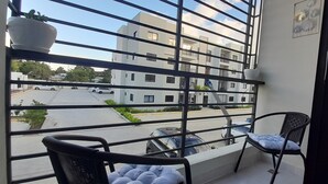 Un balcone con vista su un edificio moderno e auto parcheggiate.
