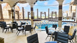 A rooftop terrace with outdoor seating, a pool, and a view of buildings. - Farhyda & Frères Hôtels  (Bangangte)