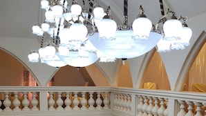 A grand lobby with a high ceiling, ornate chandeliers, and a balcony with a balustrade. - Farhyda & Frères Hôtels  (Bangangte)