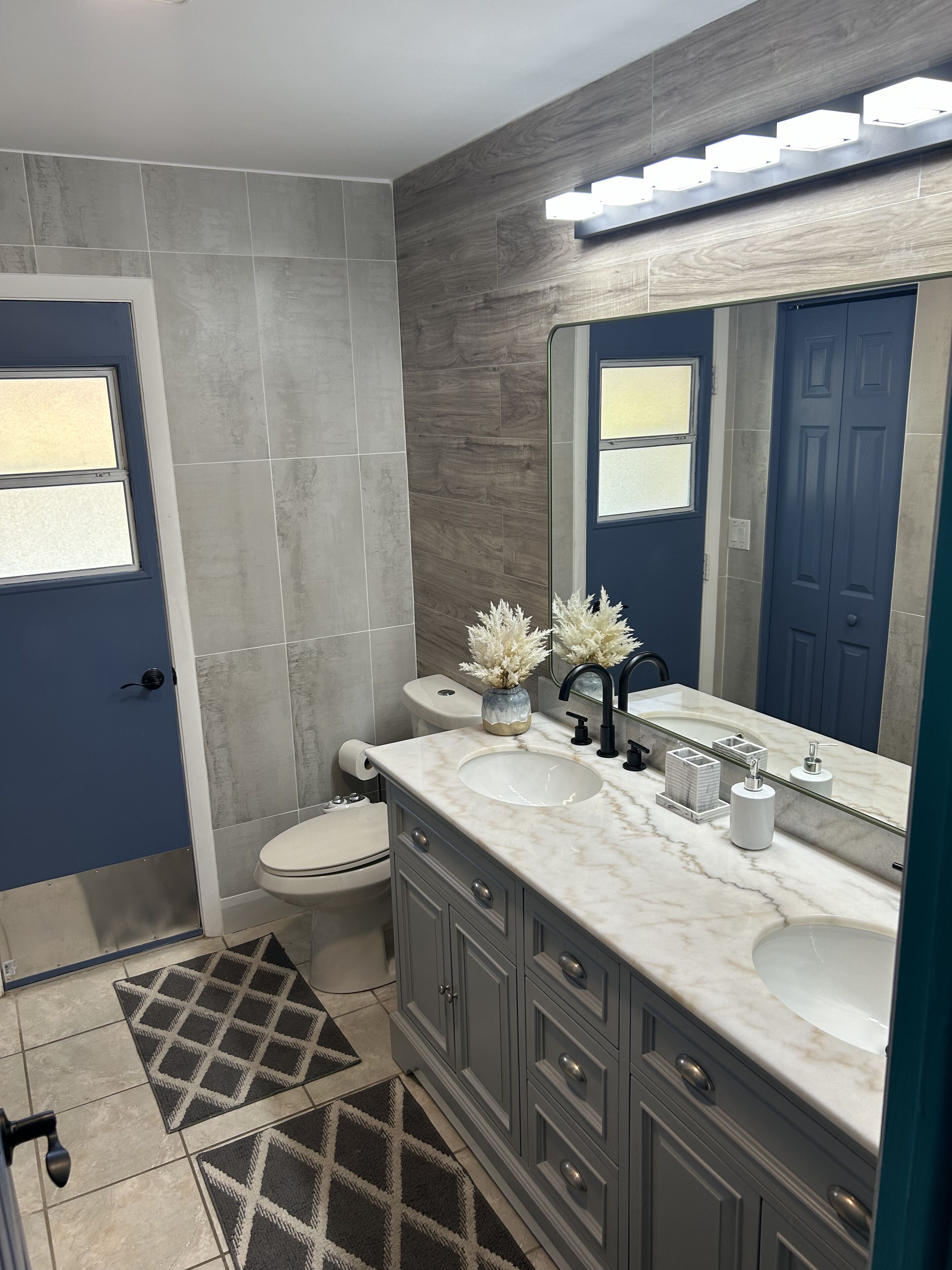 A modern bathroom with a double sink vanity, a toilet, and a shower area.