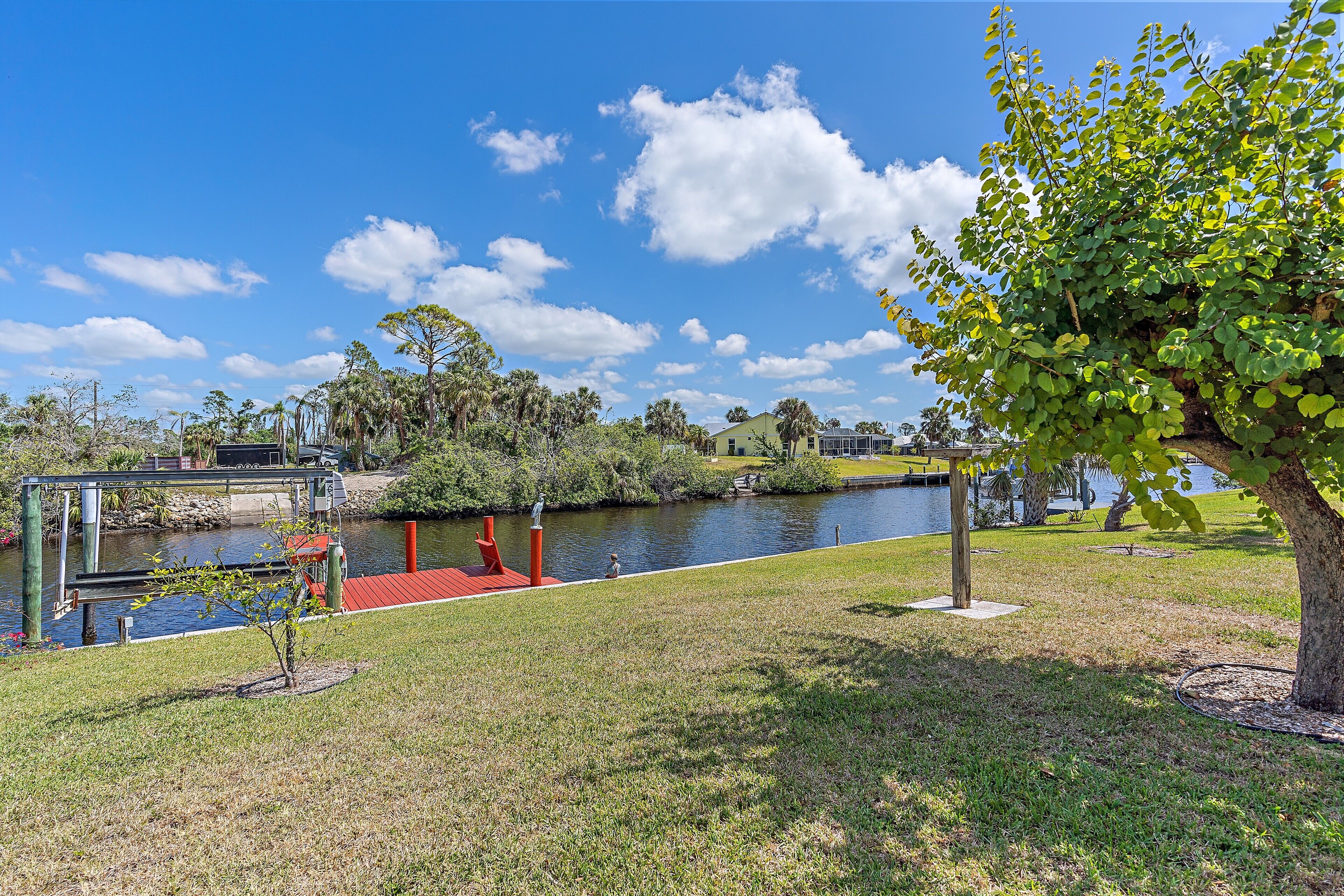 A riverside park with a bridge, a small boat dock, and a grassy area with trees.